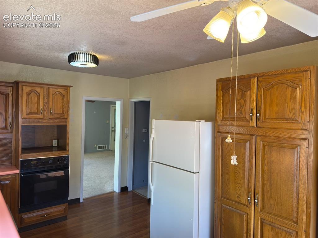 Image 34 of 48: Kitchen featuring wood-finish flooring, built-in wall oven, ceiling fan wit