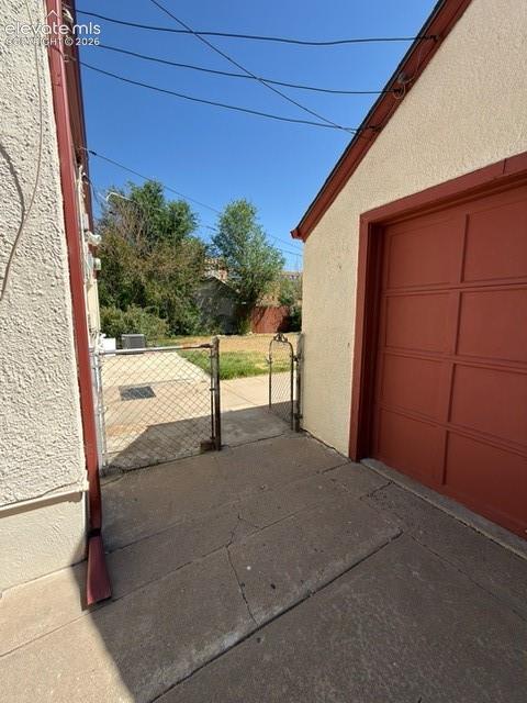 Image 42 of 48: Rear exterior featuring a detached garage with a red panel door, stucco sid
