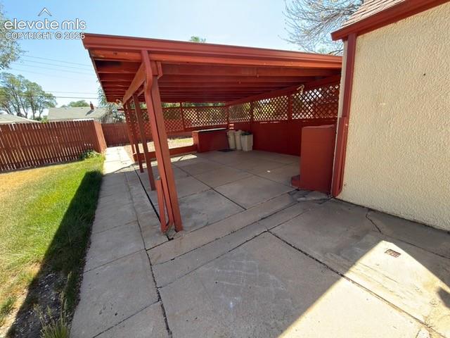 Image 46 of 48: Covered patio with a trellis privacy screen, concrete flooring, and an exte