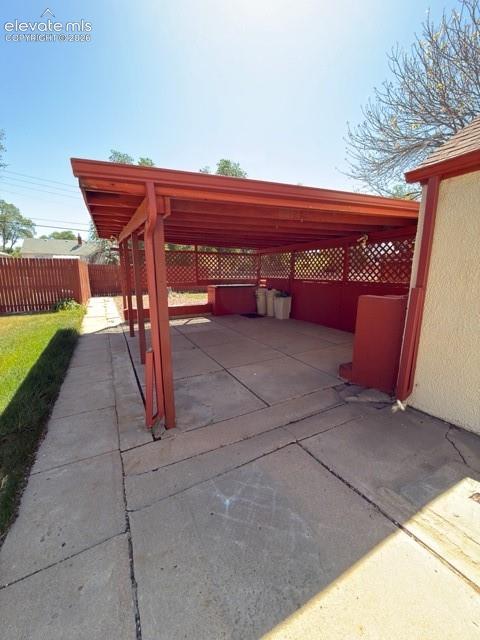 Image 47 of 48: Expansive covered patio featuring a red-painted wood frame, lattice panels,