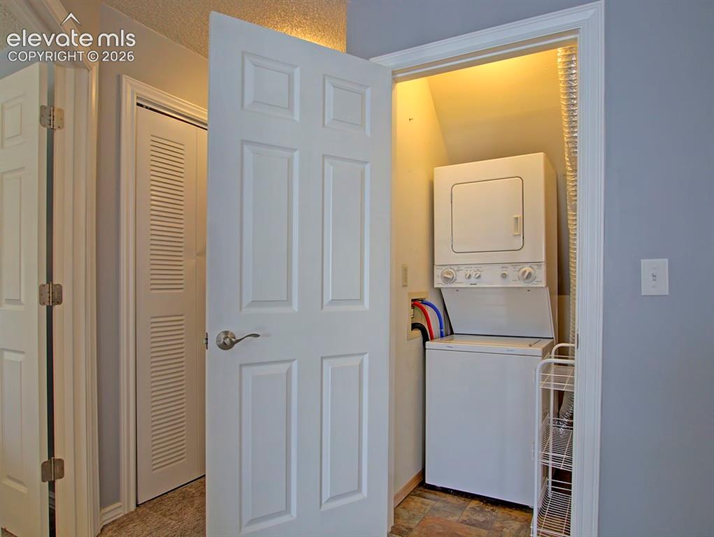 Image 13 of 13: Dedicated laundry closet featuring a white stacked washer and dryer unit, c