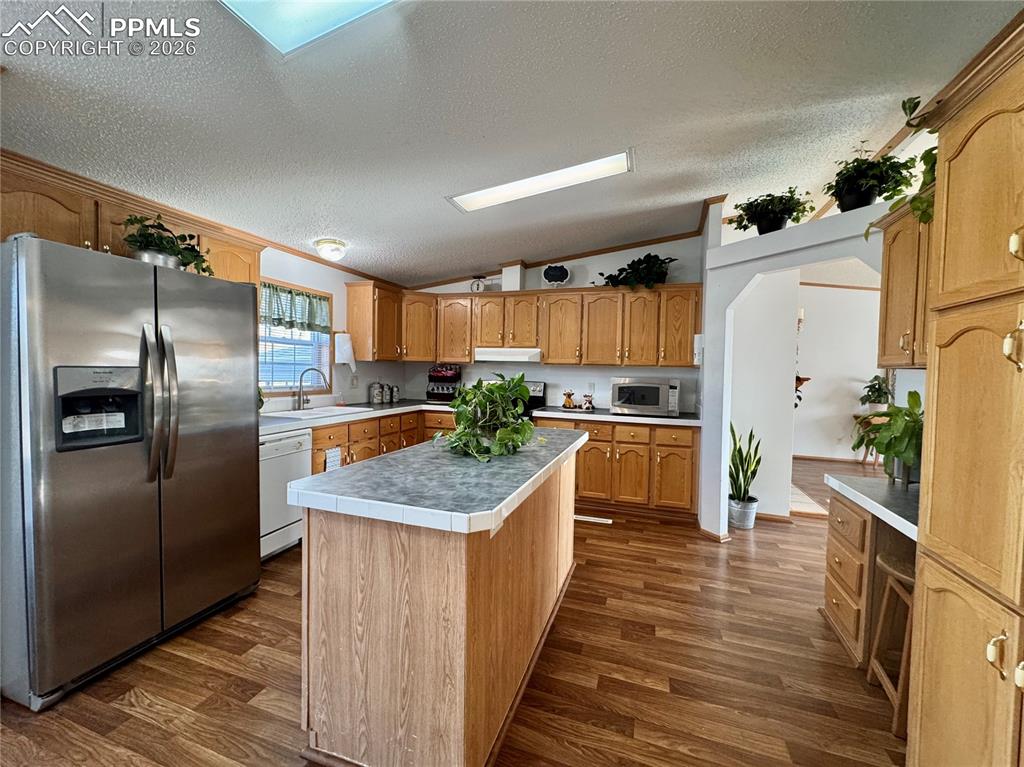 Image 10 of 44: Kitchen featuring stainless steel appliances, dark wood-type flooring, a ki