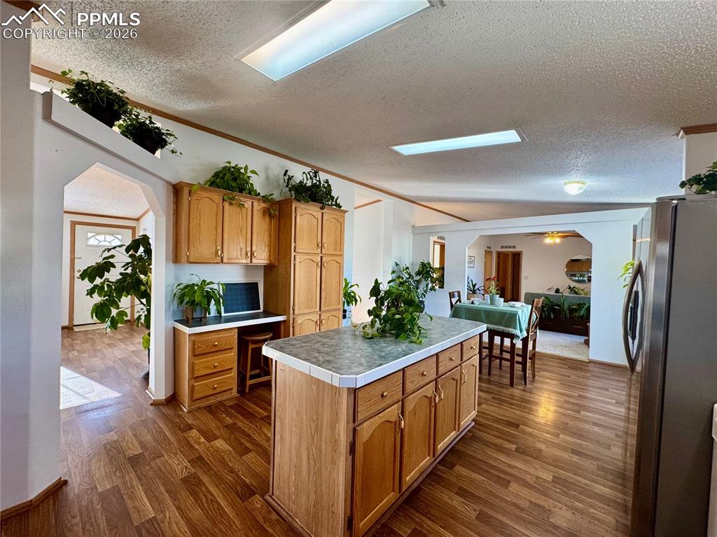 Image 12 of 44: Kitchen featuring arched walkways, freestanding refrigerator, dark wood-sty