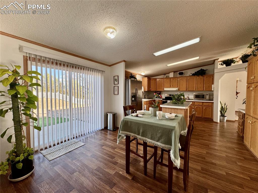 Image 14 of 44: Dining area with dark wood-style flooring and crown molding