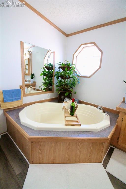 Image 32 of 44: Full bath with a garden tub, ornamental molding, wood finished floors, a te