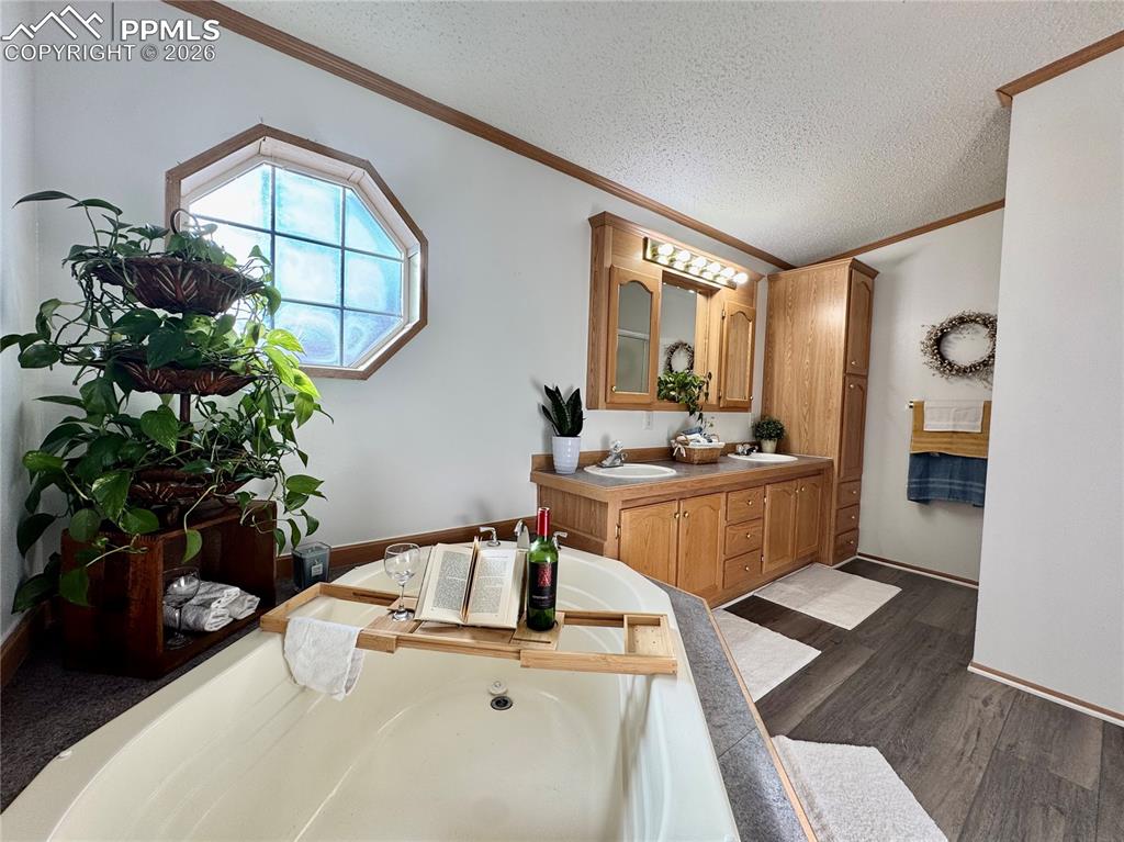 Image 33 of 44: Full bathroom featuring double vanity, a garden tub, dark wood-style floori