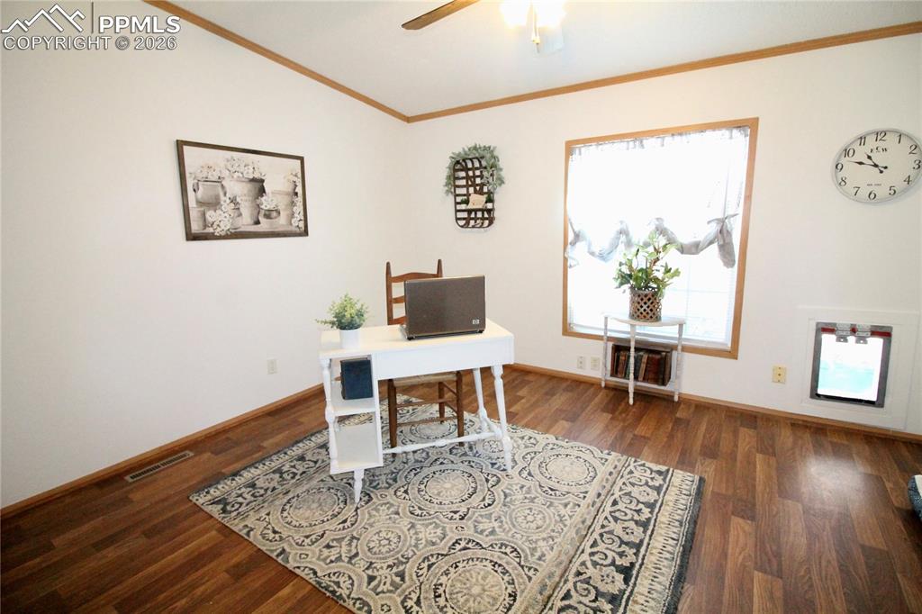 Image 34 of 44: Home office featuring dark wood-style flooring, ornamental molding, and a c