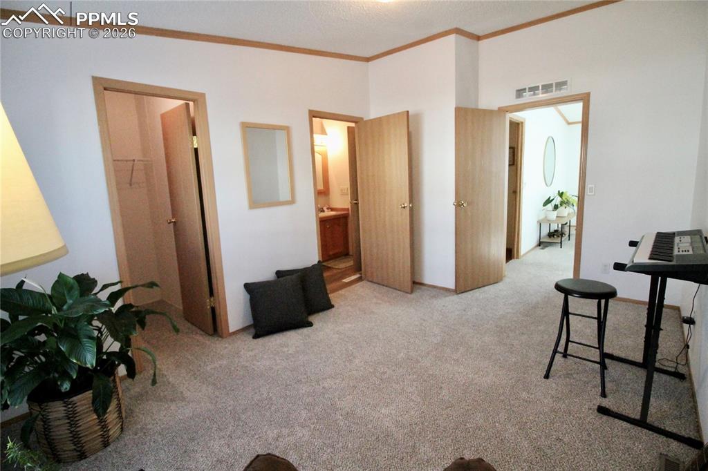 Image 37 of 44: Home office featuring light colored carpet, ornamental molding, and a textu