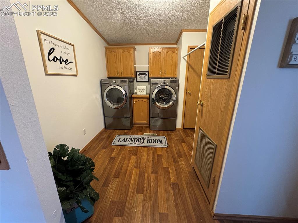 Image 40 of 44: Laundry area featuring cabinet space, dark wood-style floors, a textured ce