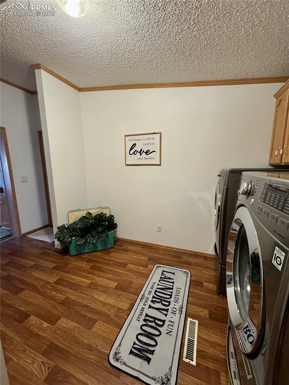 Image 41 of 44: Laundry room featuring dark wood-style flooring, washer and dryer, a textur
