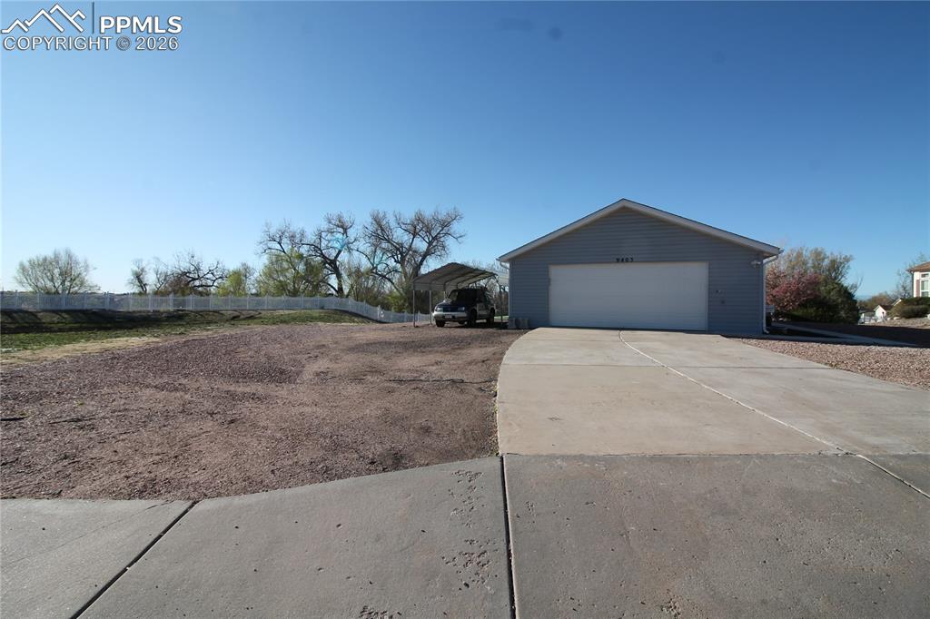 Image 42 of 44: View of side of property featuring driveway, an outdoor structure, and a de