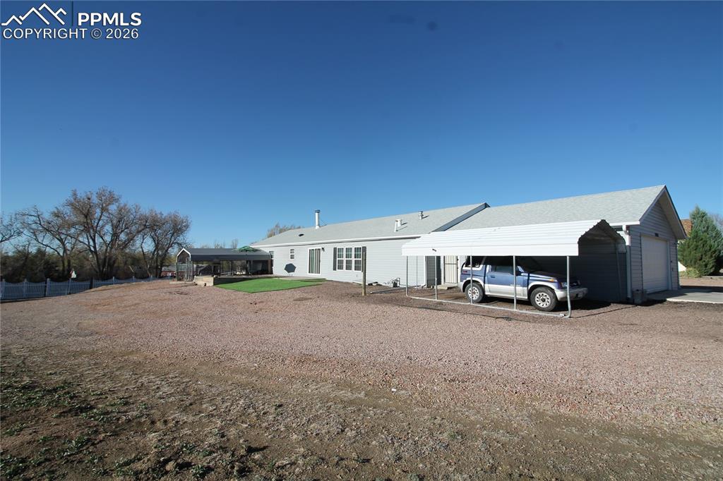 Image 43 of 44: Back of house with a detached carport and driveway