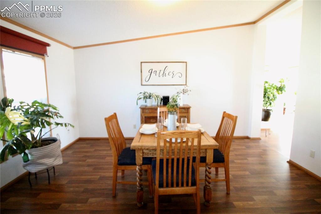 Image 8 of 44: Dining area with dark wood-style floors and crown molding