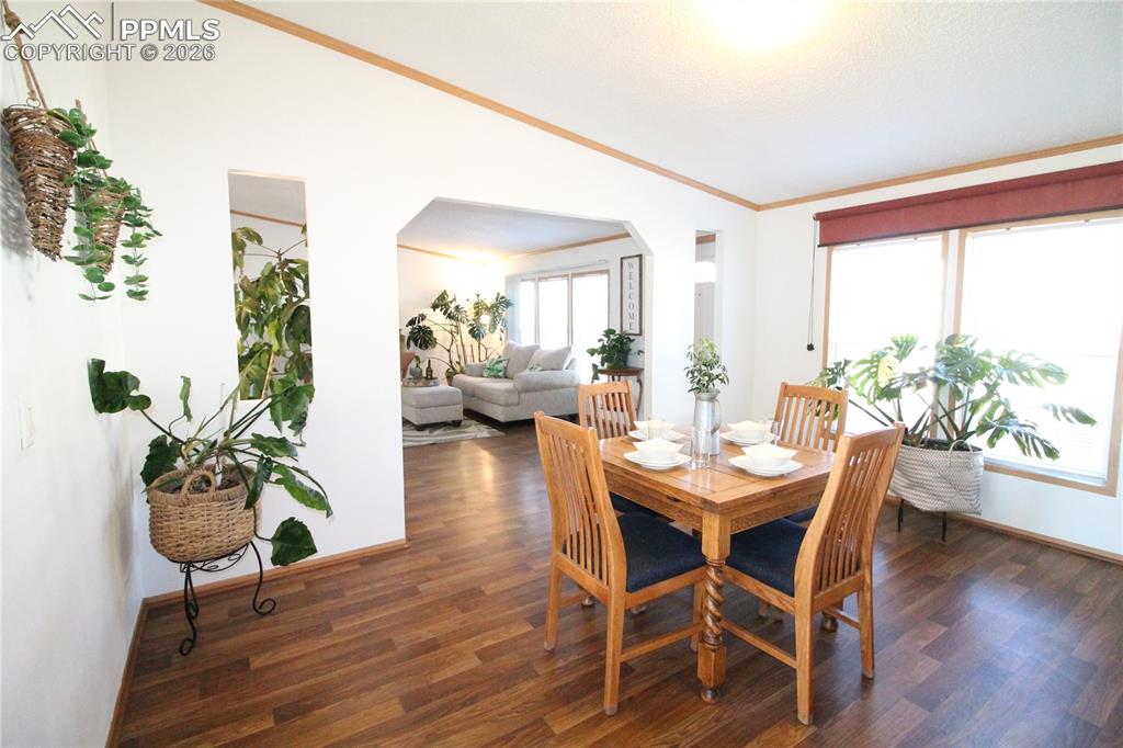 Image 9 of 44: Dining space featuring lofted ceiling, arched walkways, dark wood-type floo