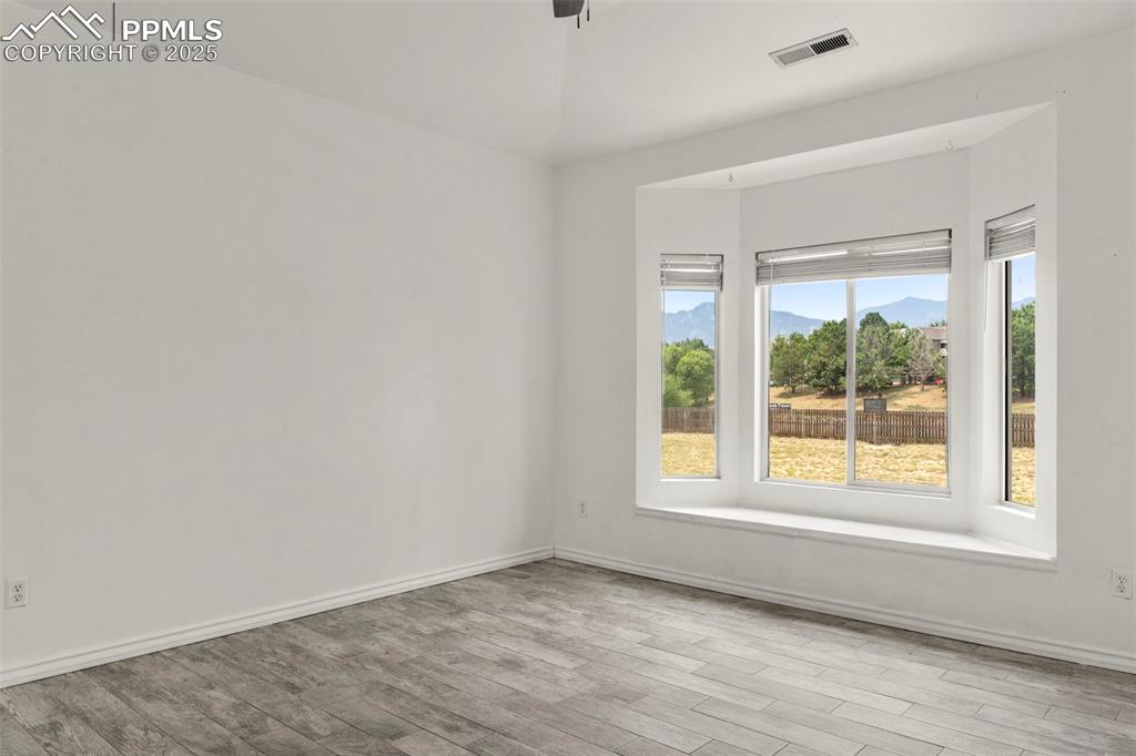 Image 10 of 15: Empty room with plenty of natural light, wood finished floors, and a mounta
