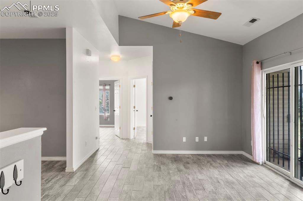 Image 2 of 15: Unfurnished room featuring light wood-style floors, a ceiling fan, and vaul