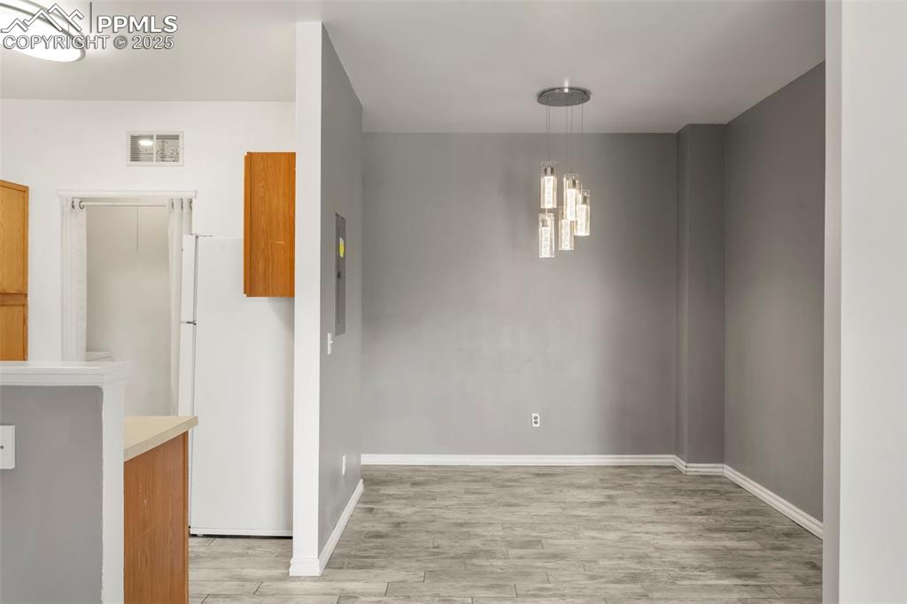 Image 5 of 15: Unfurnished dining area featuring light wood-style flooring and a chandelie