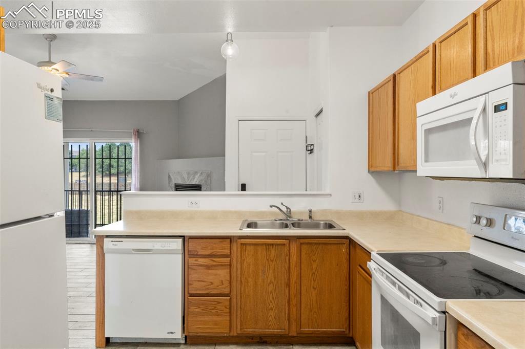 Image 7 of 15: Kitchen with white appliances, a peninsula, a ceiling fan, light countertop