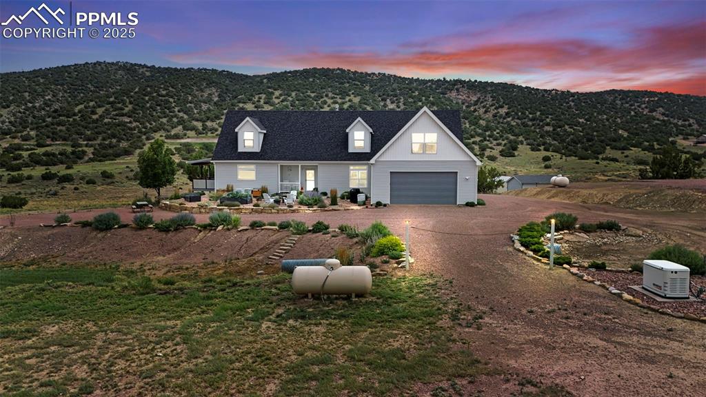 Caption: Modern farmhouse style home featuring dirt driveway, a mountain view, and a garage