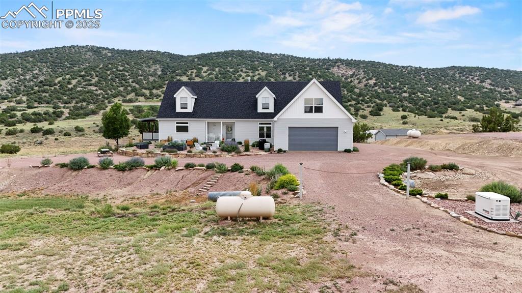 Image 15 of 41: Modern farmhouse featuring dirt driveway, a mountain view, and a garage
