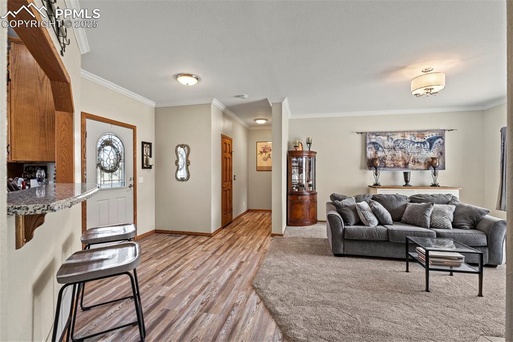Image 16 of 41: Living area featuring light wood-style flooring and ornamental molding
