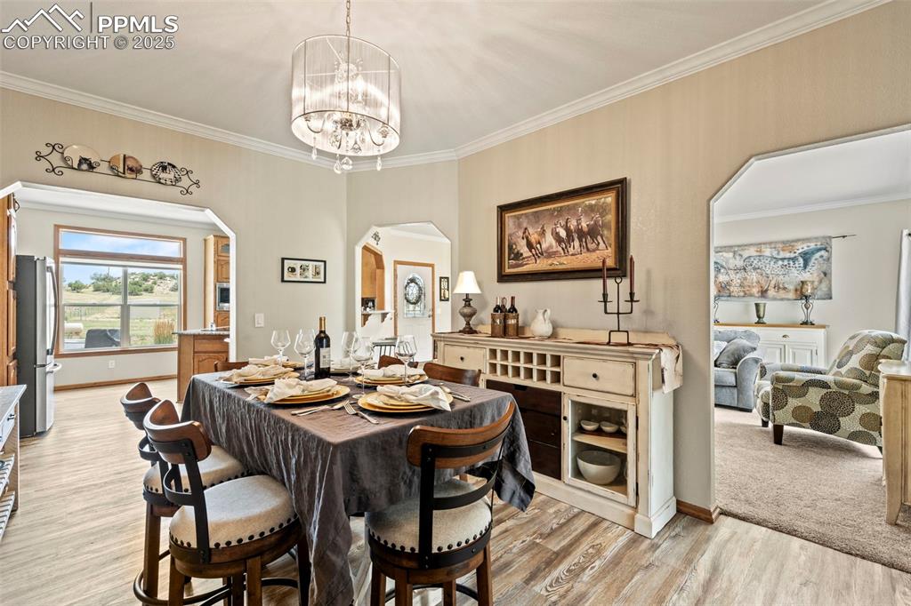 Image 21 of 41: Dining space featuring arched walkways, ornamental molding, a chandelier, a