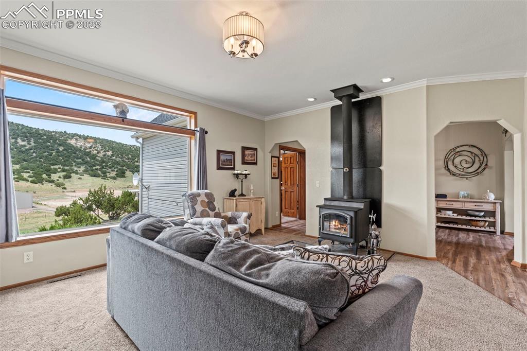 Image 22 of 41: Living area featuring arched walkways, ornamental molding, a wood stove, ca