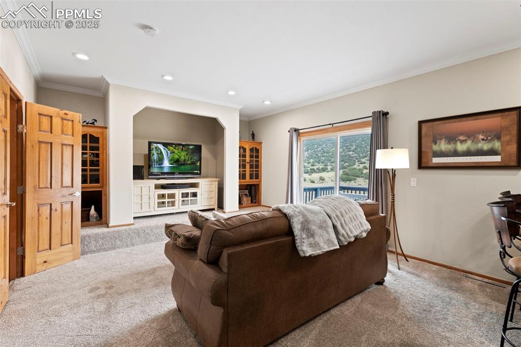 Image 24 of 41: Carpeted living area featuring crown molding and recessed lighting