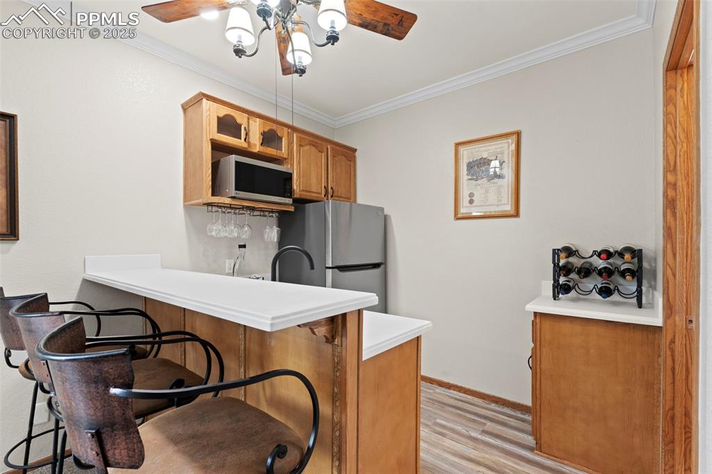 Image 25 of 41: Kitchen featuring a ceiling fan, light wood-type flooring, ornamental moldi