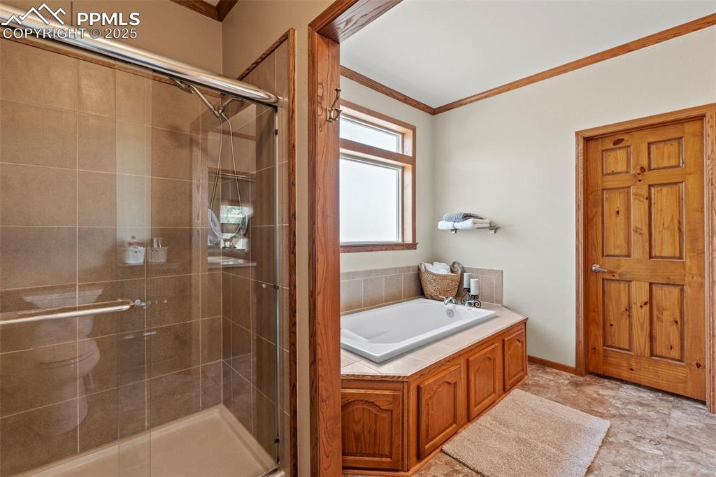 Image 28 of 41: Full bath with crown molding, a bath, and a stall shower
