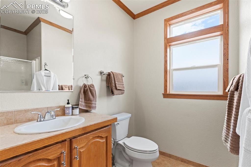 Image 34 of 41: Bathroom featuring crown molding, vanity, and a stall shower