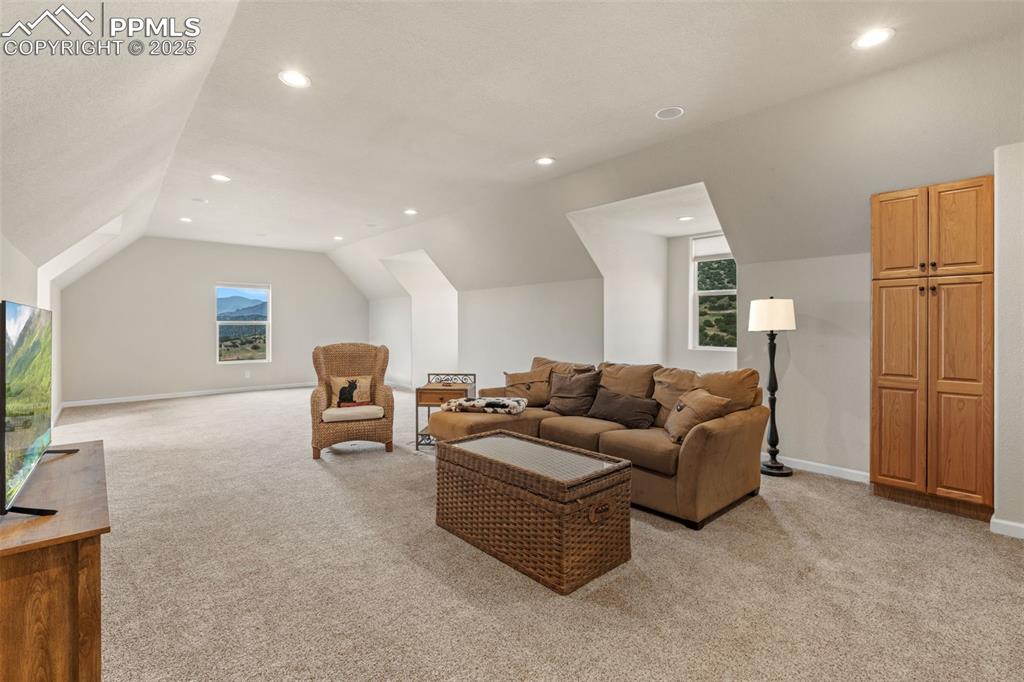 Image 37 of 41: Living area featuring light carpet, vaulted ceiling, and recessed lighting