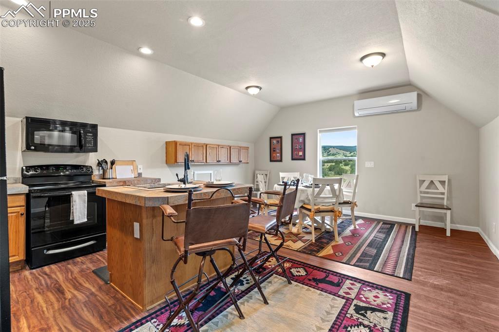 Image 38 of 41: Kitchen featuring black appliances, lofted ceiling, dark wood-style floorin