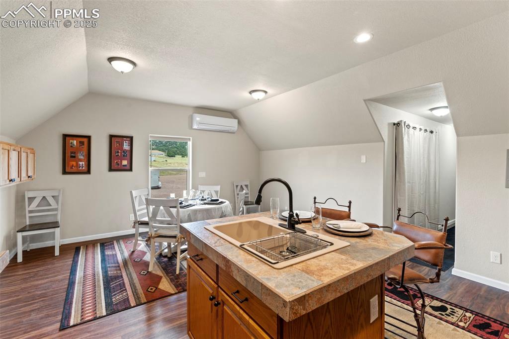 Image 39 of 41: Kitchen with dark wood-style flooring, vaulted ceiling, brown cabinetry, an