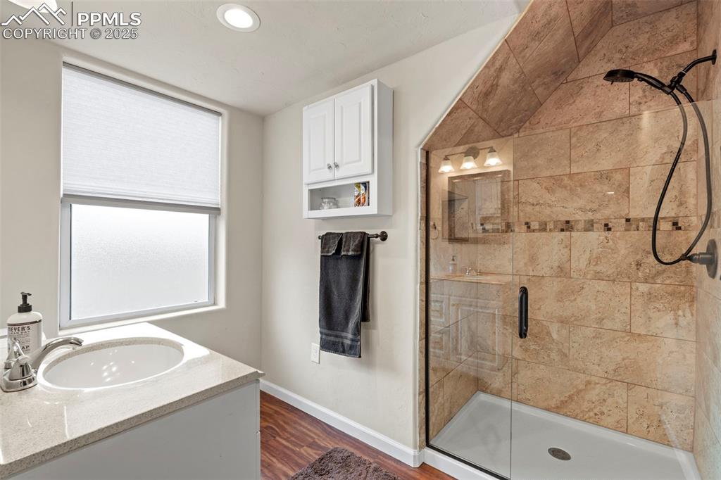 Image 40 of 41: Bathroom with a stall shower, wood finished floors, vanity, and recessed li