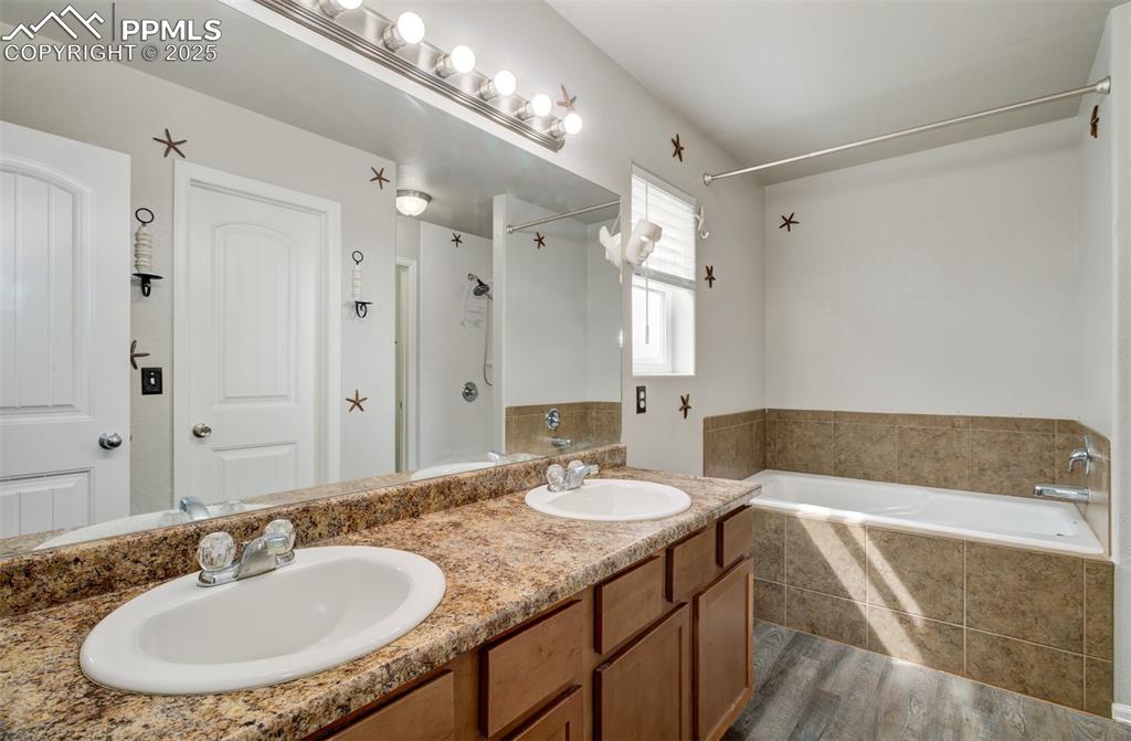 Image 26 of 35: Bathroom with dark wood-style floors and double vanity