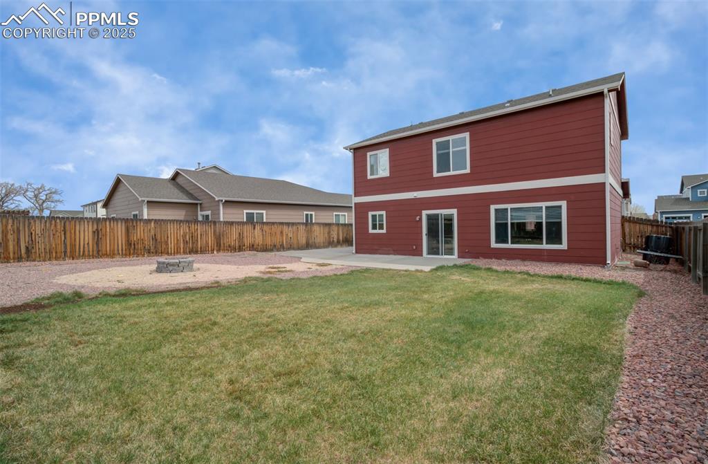 Image 29 of 35: Back of property featuring a patio, a fenced backyard, and an outdoor fire 