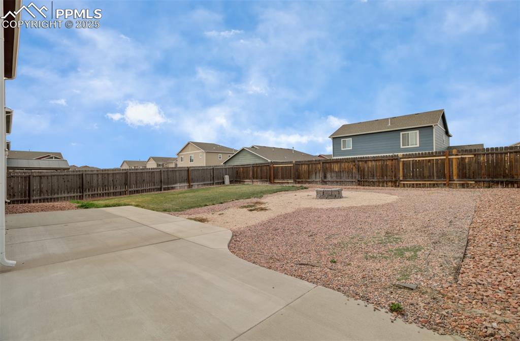 Image 34 of 35: Fenced backyard with an outdoor fire pit, a patio, and a residential view