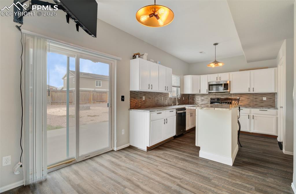 Image 6 of 35: Kitchen with hanging light fixtures, a kitchen island, dark wood finished f