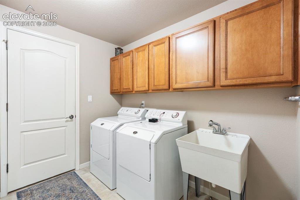 Image 16 of 50: Main level laundry room, Maytag washer and dryer, sink, door to garage