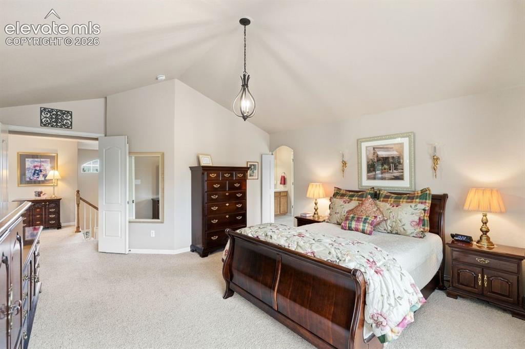 Image 4 of 50: Primary bedroom with vaulted ceiling and french doors