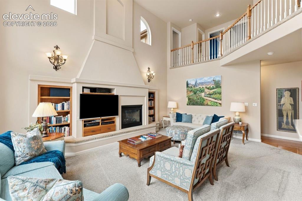 Image 7 of 50: Family room with wall of windows, ceiling fan, and built in fireplace with 