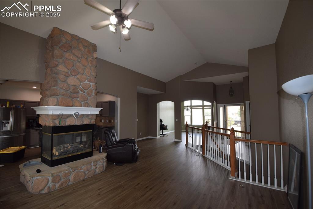 Image 11 of 50: Living area with wood finished floors, a fireplace, arched walkways, ceilin