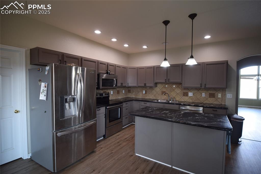 Image 13 of 50: Kitchen featuring stainless steel appliances, dark wood-style floors, taste