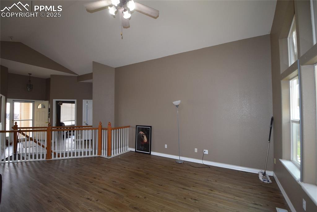 Image 18 of 50: Empty room with wood finished floors, ceiling fan, and high vaulted ceiling