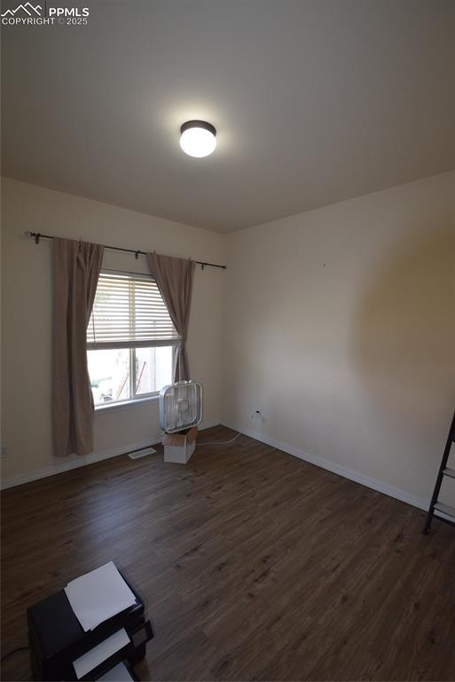 Image 23 of 50: Spare room featuring dark wood-style flooring and baseboards