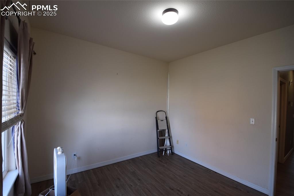Image 24 of 50: Empty room featuring dark wood-style floors and baseboards