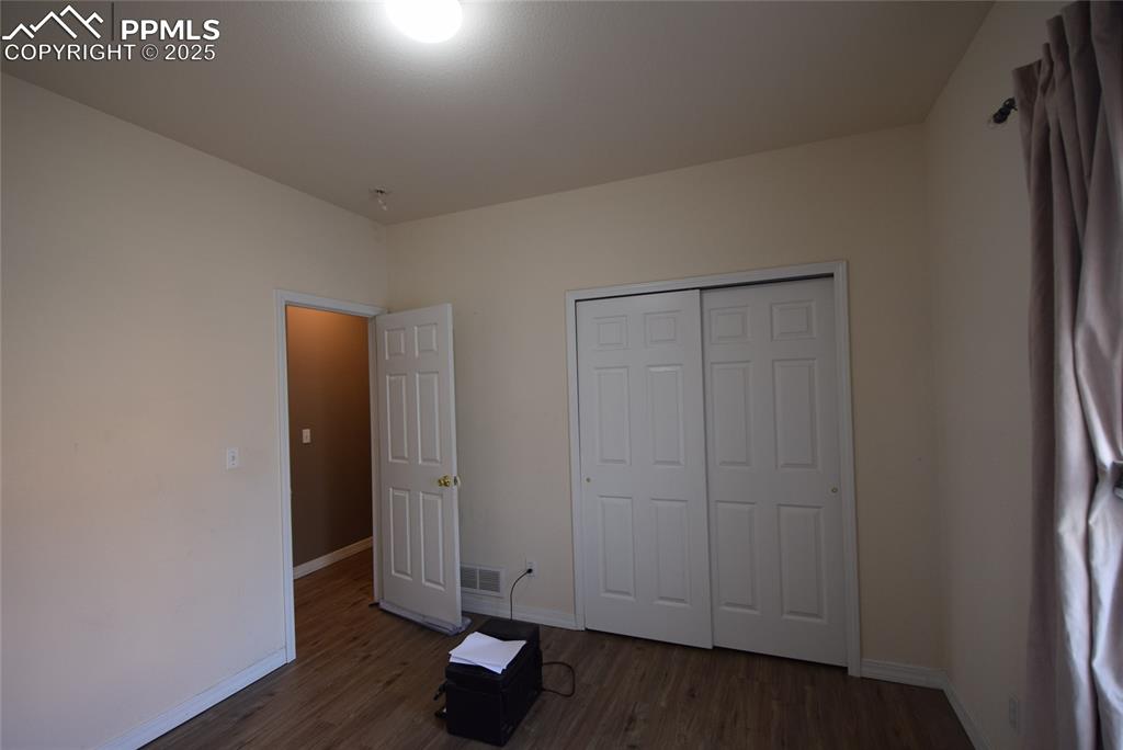 Image 25 of 50: Unfurnished bedroom with dark wood-style flooring and a closet