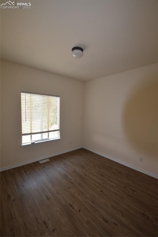 Image 26 of 50: Unfurnished room featuring dark wood finished floors and baseboards