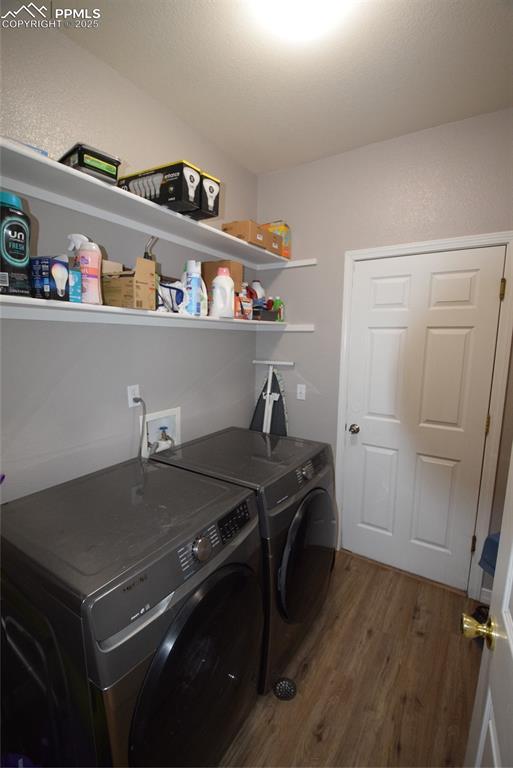 Image 29 of 50: Washroom featuring washer and clothes dryer and wood finished floors
